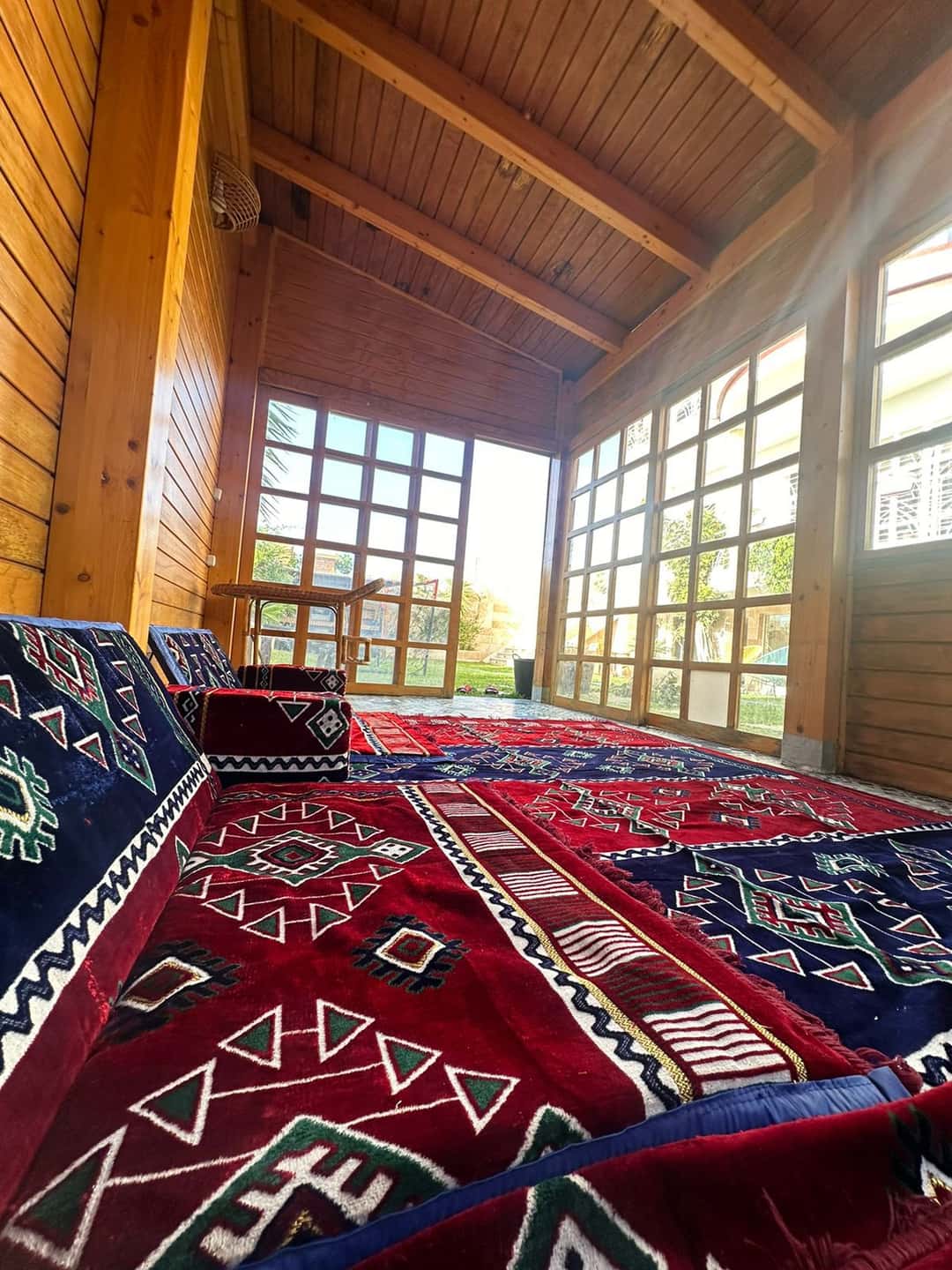 The red and blue diamond rug spread on the floor, its four seats set around it